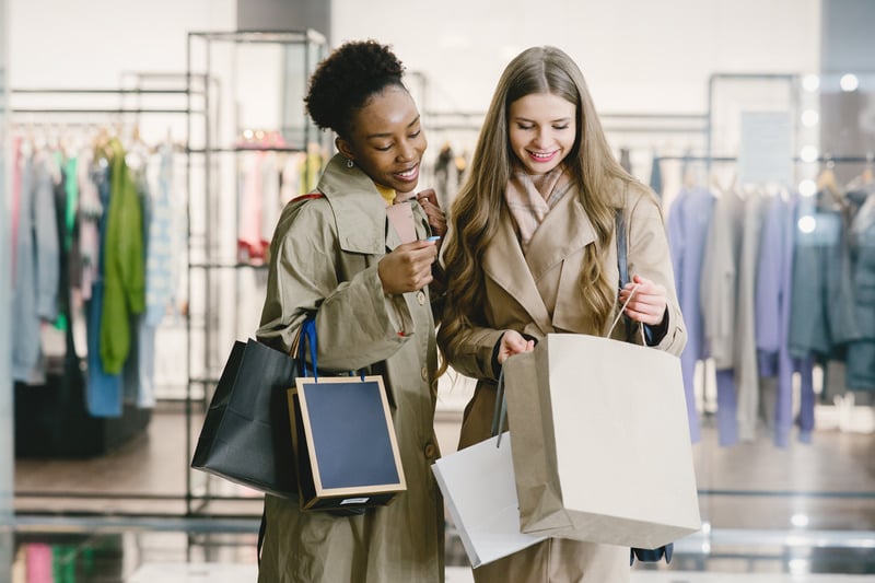 Two friends looking into a shopping bag inside a clothing store
