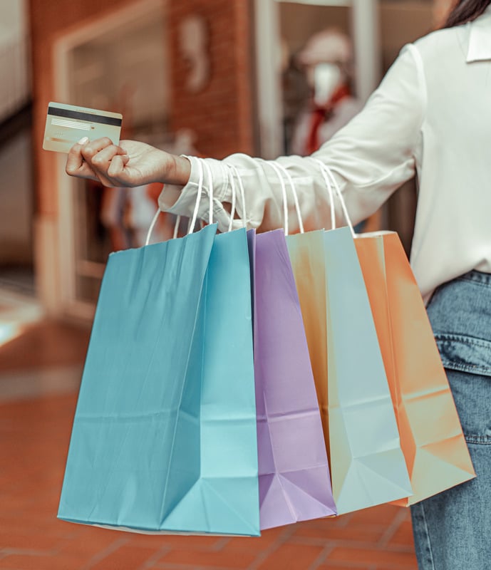 Shopper holding a payment card and a handful of paper bags