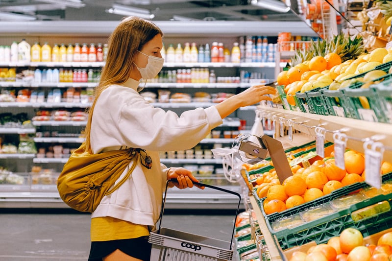 Shopper picking fresh produce in a supermarket aisle